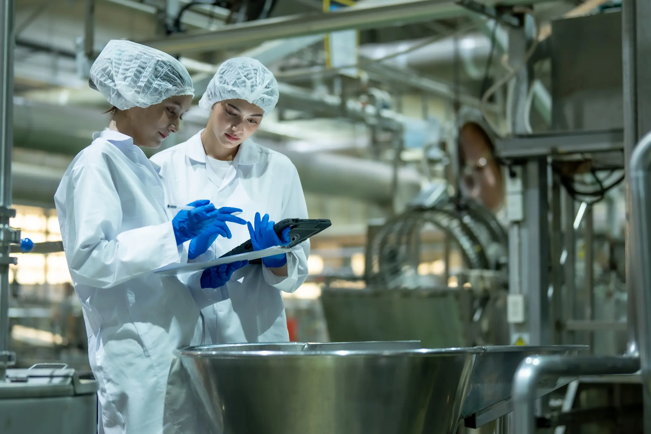 Workers in a factory checking a tablet.
