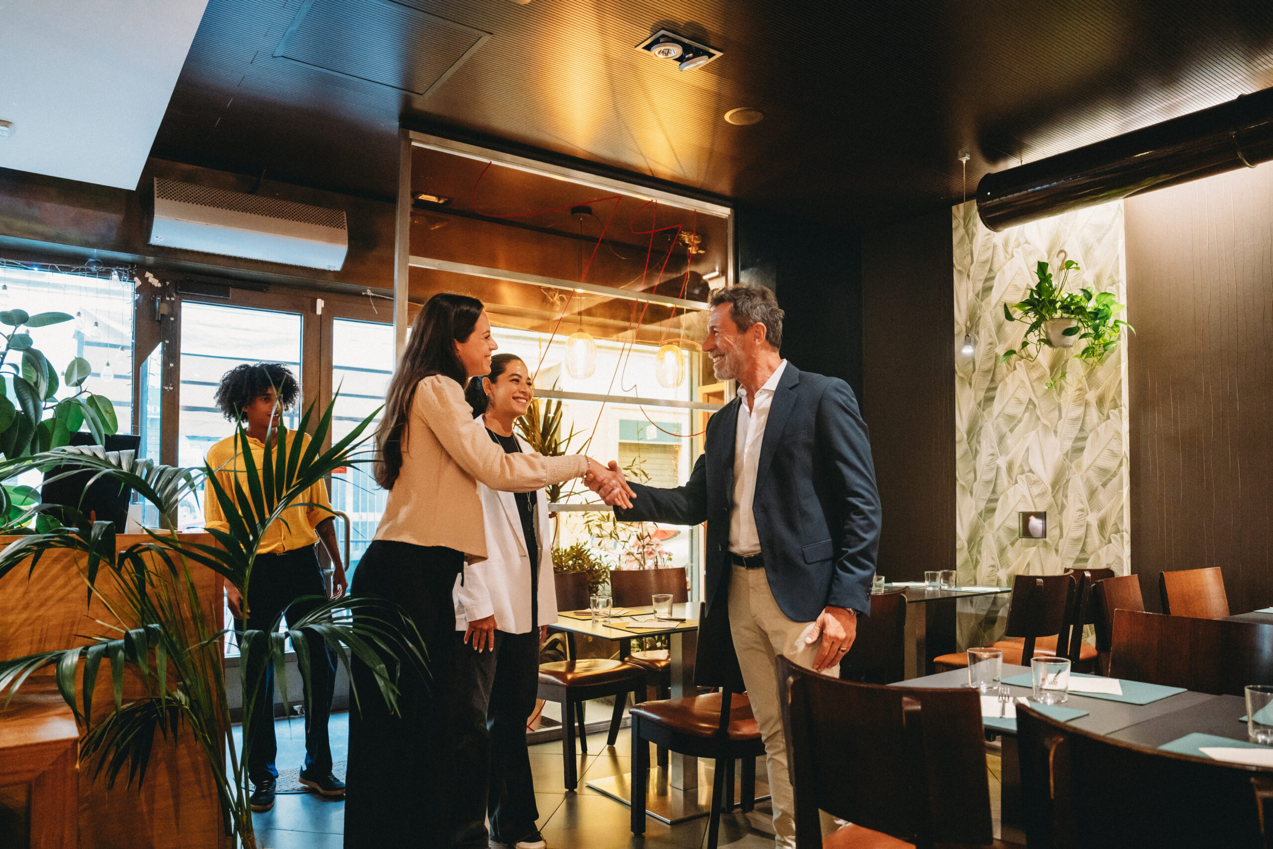 People shaking hands in a restaurant setting.
