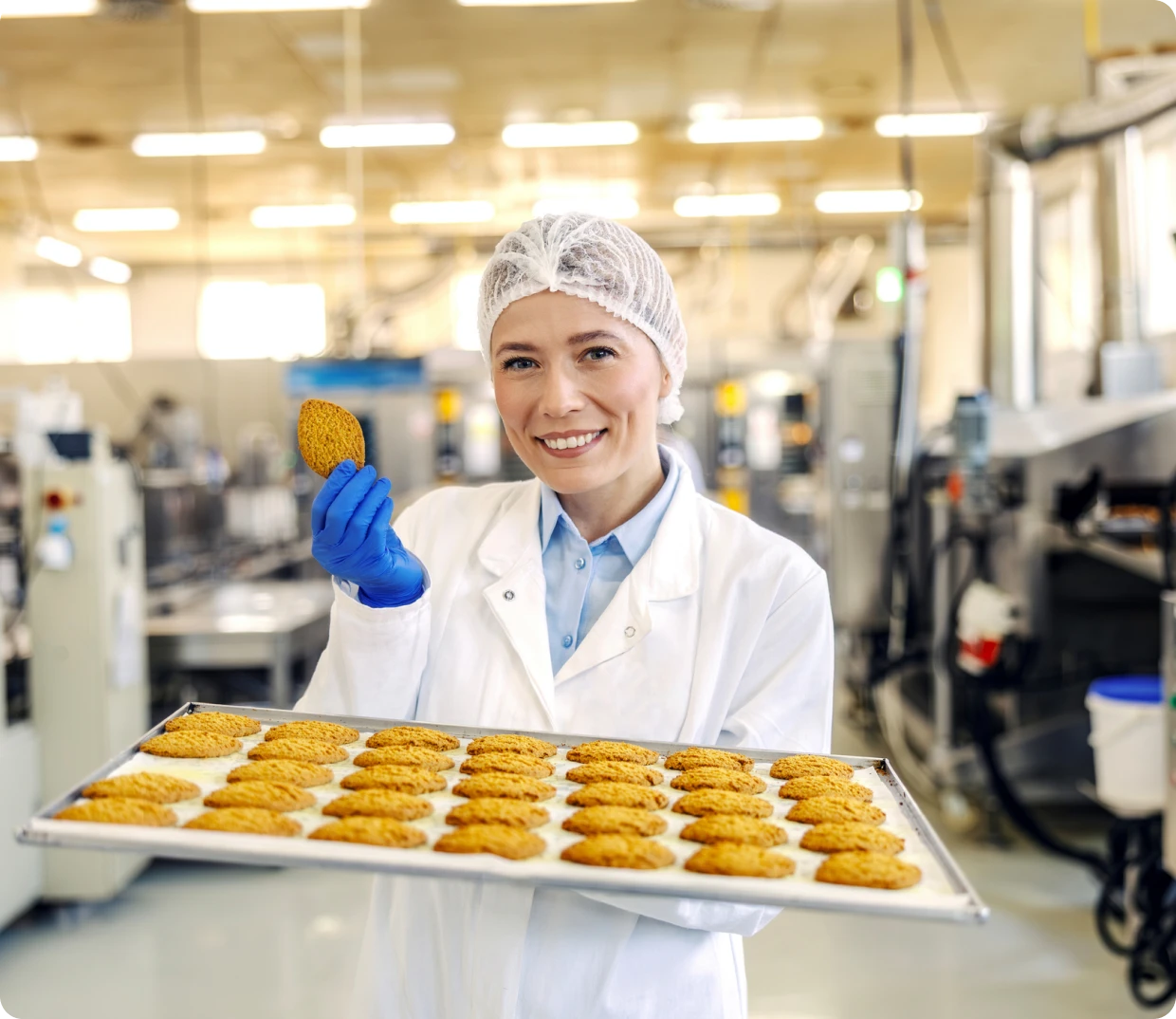 Factory worker holding tray of cookies
