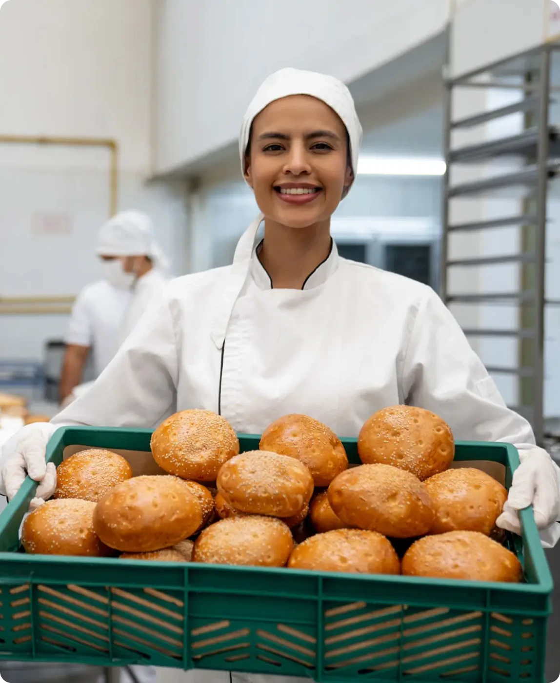 Baker holding tray of fresh bread rolls
