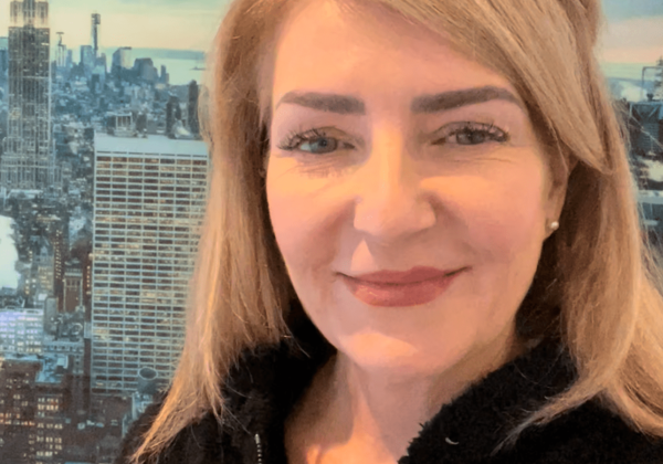 Woman smiling with New York City backdrop.
