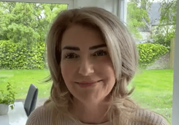 Woman smiling in bright room with garden.