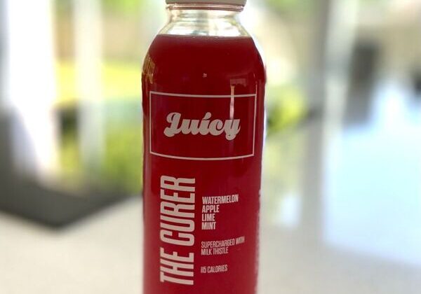 Red juice bottle on a white surface.