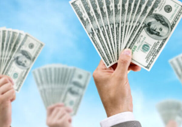 Hands holding stacks of hundred-dollar bills.