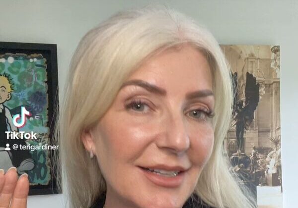 Woman smiling with framed art behind her.