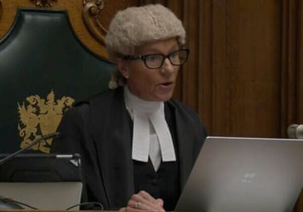 Judge in courtroom with laptop and documents.