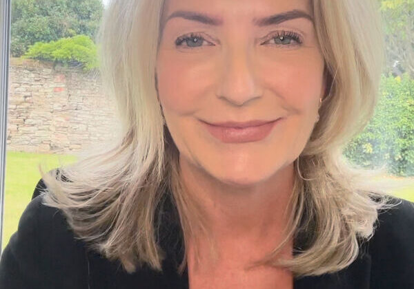 Smiling woman with blonde hair indoors.