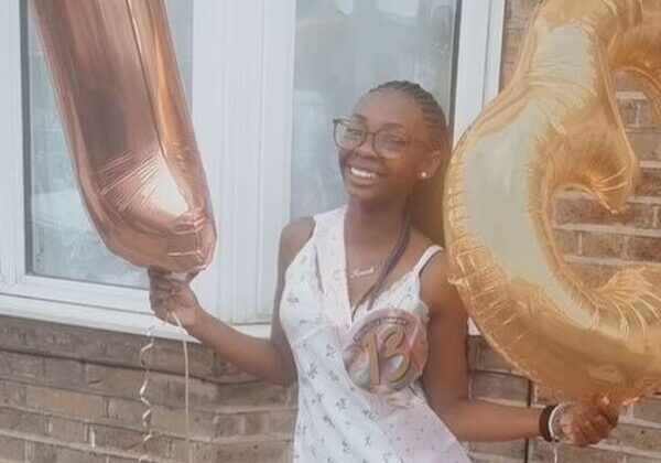 Smiling woman holding large gold balloons.