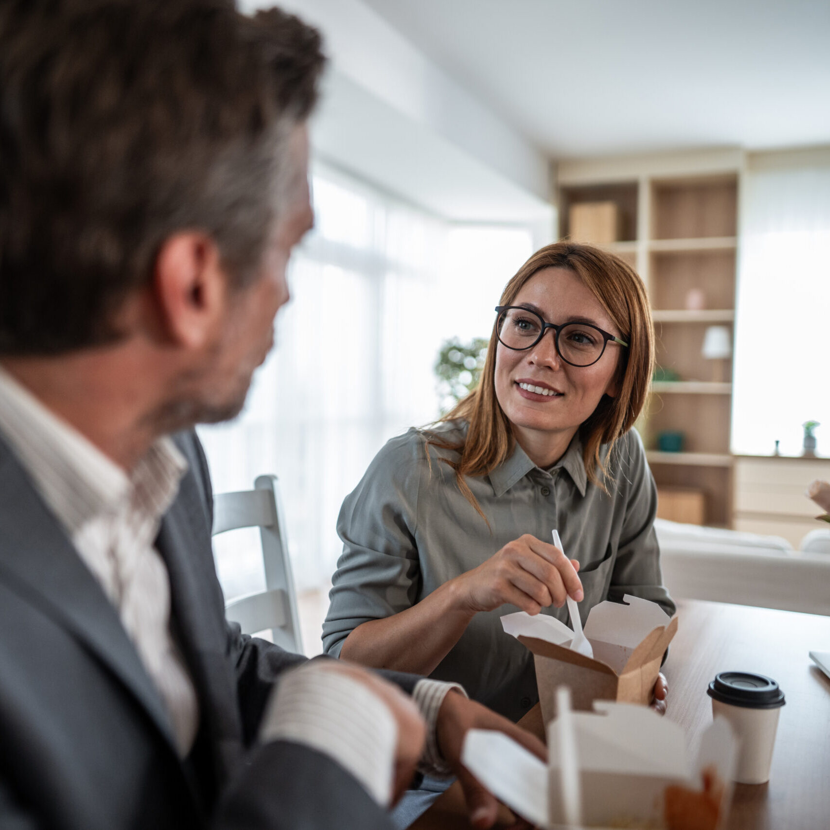 Two people eating and talking at table.
